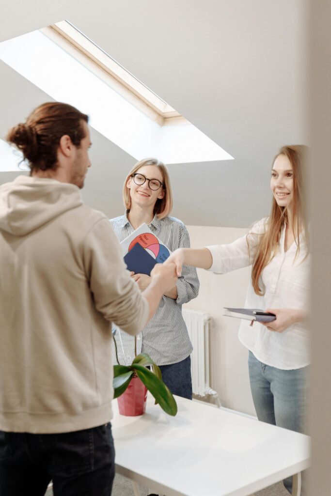 Colleagues greet each other with a handshake in a bright modern office space, depicting teamwork and cooperation.